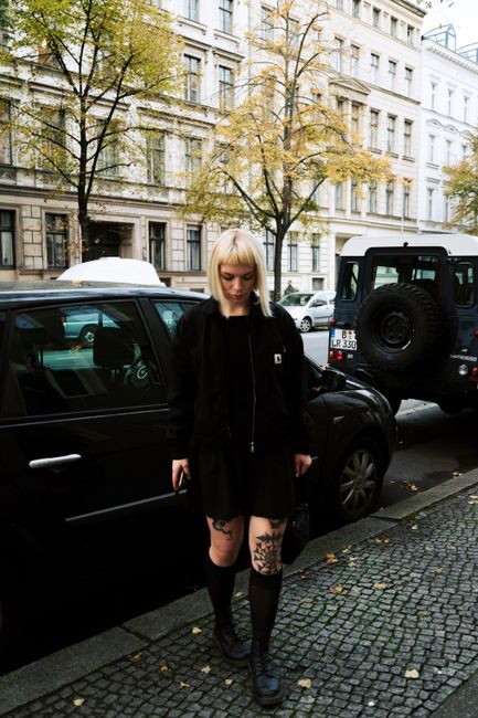 Woman with blonde hair and tattoos walking in Berlin street during autumn.