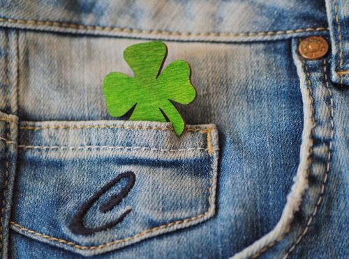 Free Close-up of a green clover decoration in a blue denim pocket. Represents luck and casual style. Stock Photo