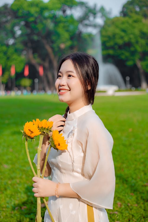 Smiling Young Model in a Traditional White Split Tunic Holding Sunflowers