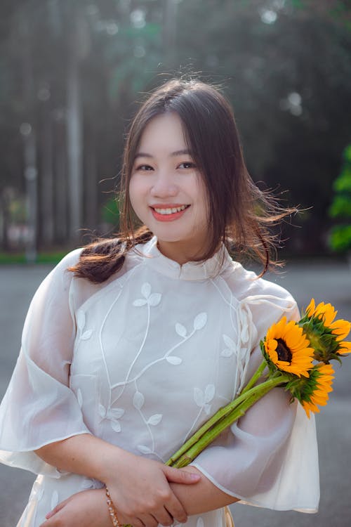 Model in an Embroidered White Dress Posing with Sunflowers