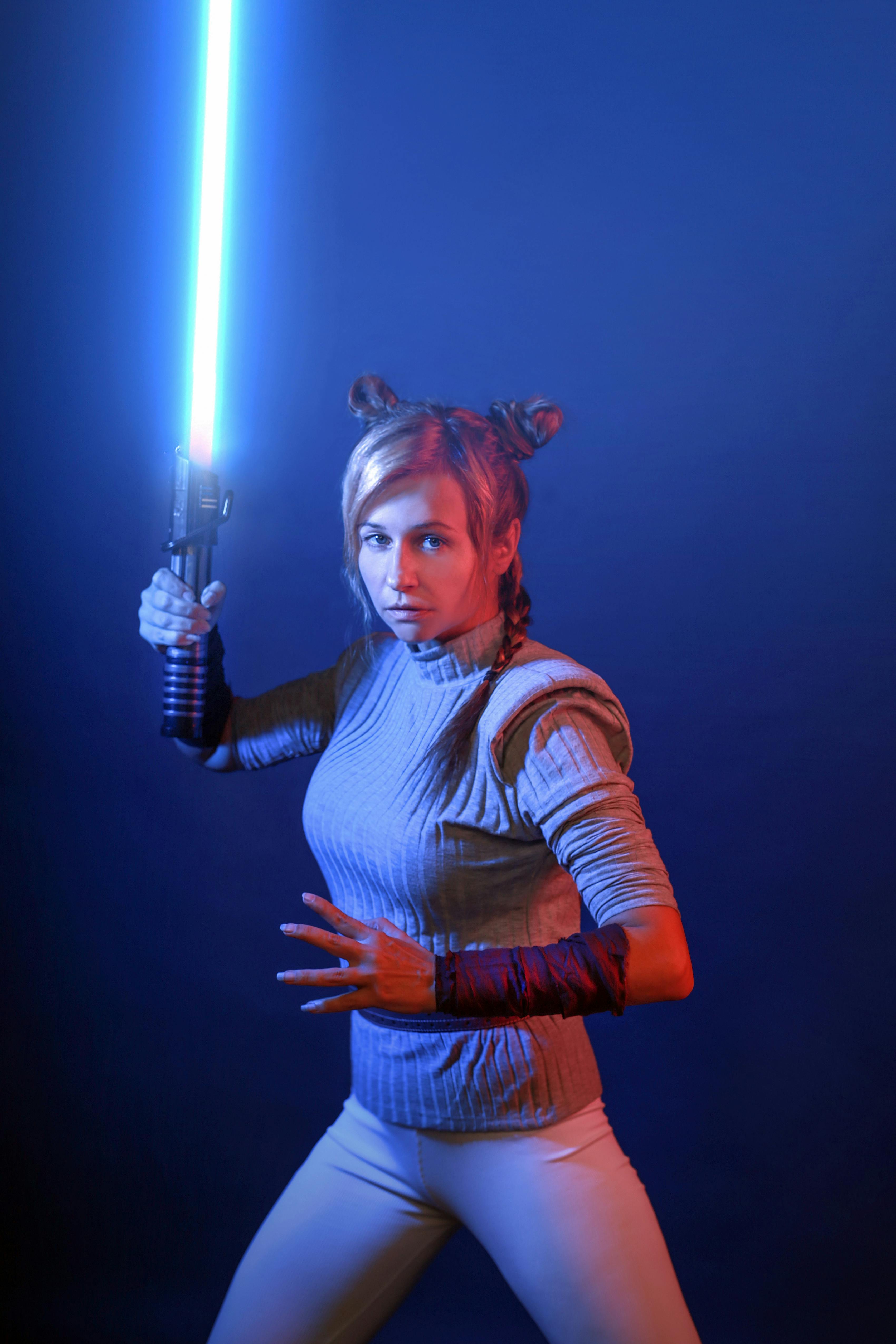 A woman dressed in a star wars costume holding a light sabed sword ...