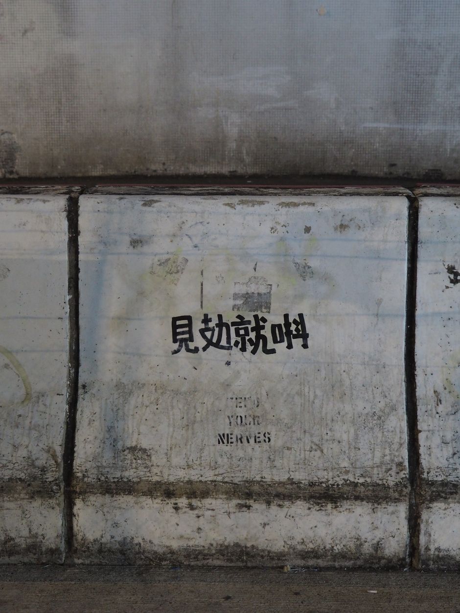 Concrete wall with graffiti text in Hong Kong, showcasing urban decay and street art culture.