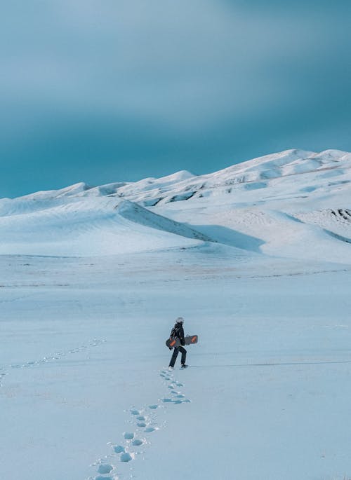 Person Walking with Snowboard in Snow