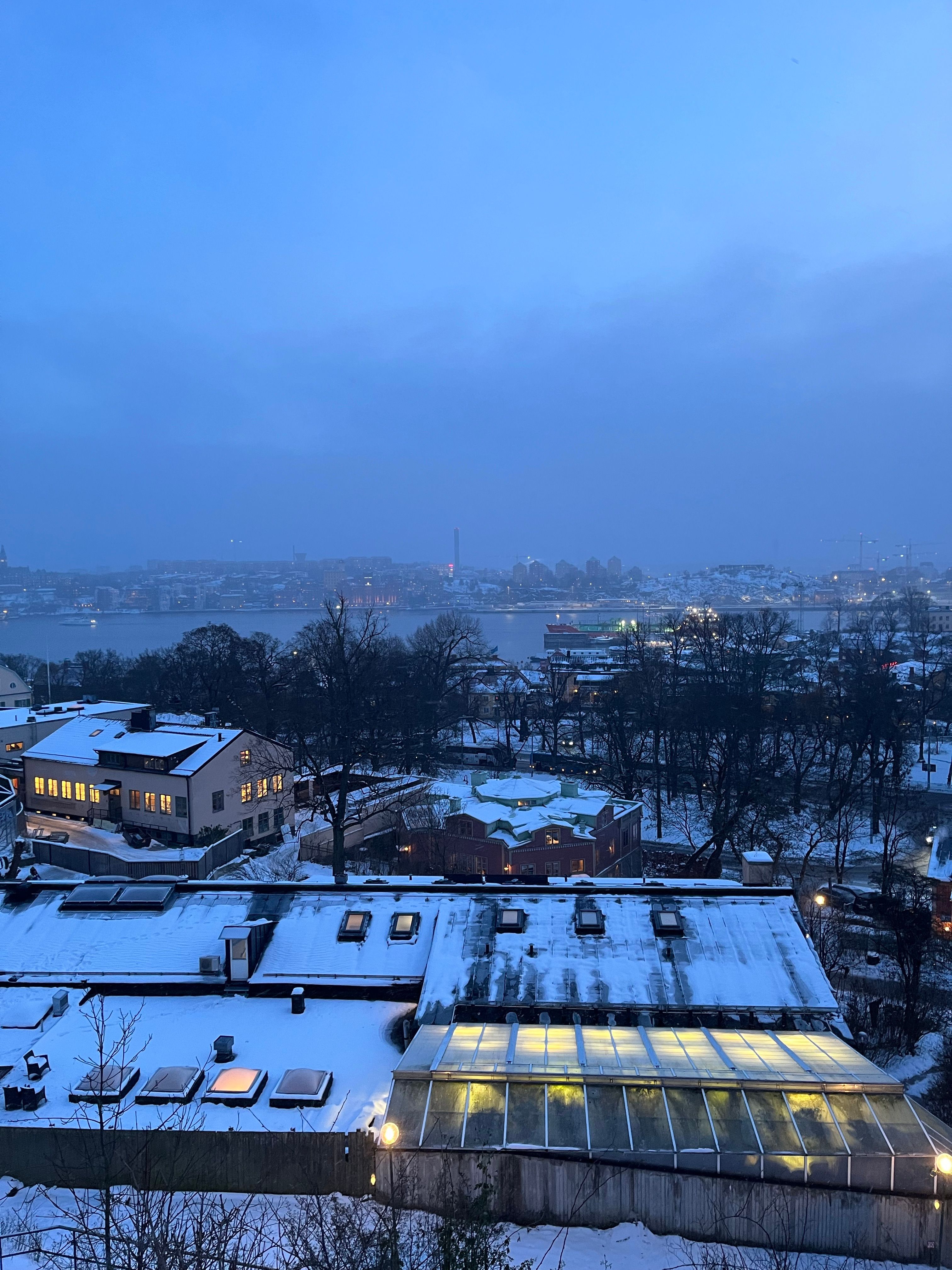 Aerial view of Stockholm with snow-covered rooftops at dusk, showcasing winter cityscape.