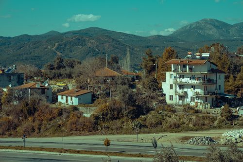 Free Charming rural village surrounded by hills and mountains, showcasing a serene countryside view. Stock Photo