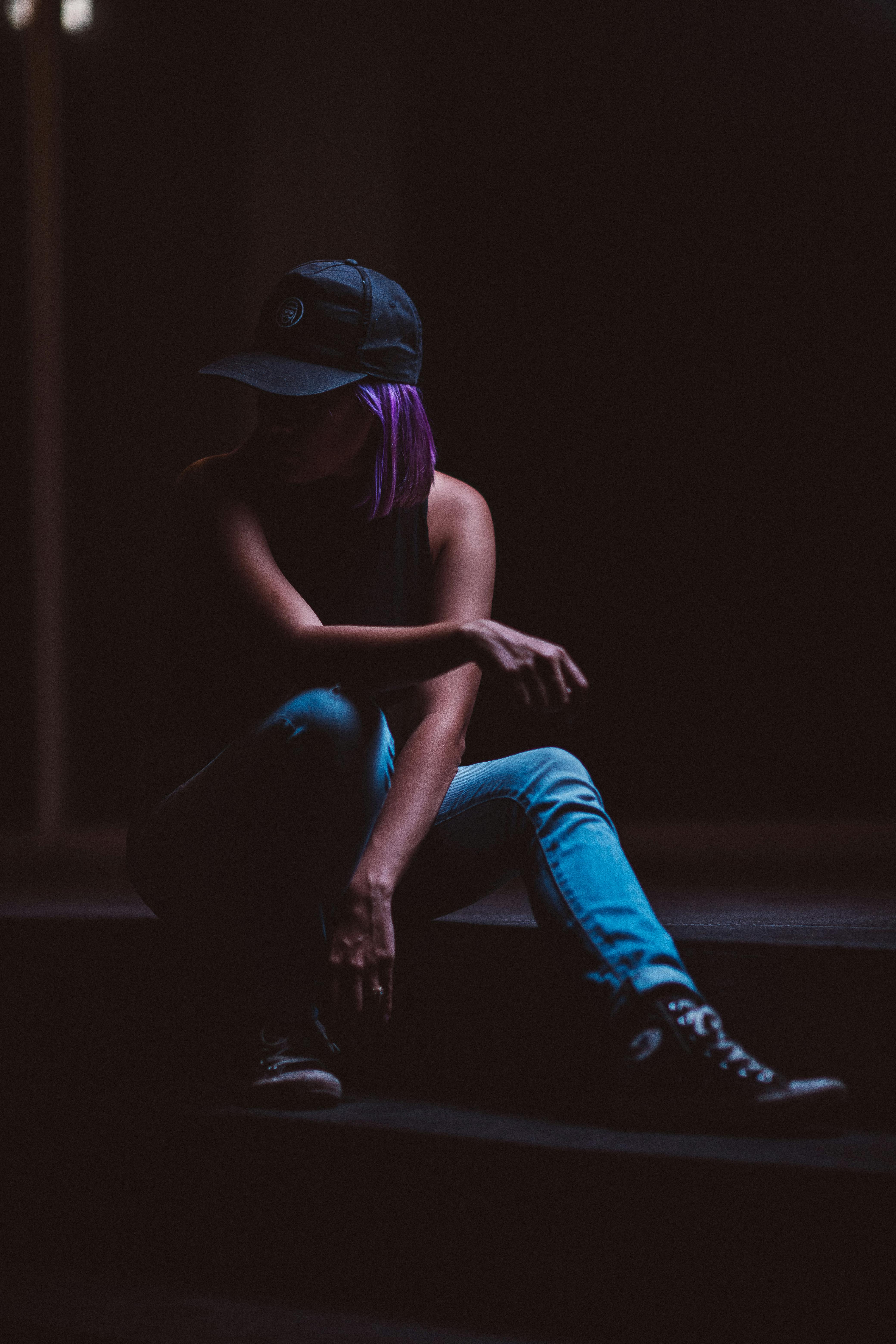 一名女子穿着休闲装，在光线昏暗的环境中若有所思地坐着