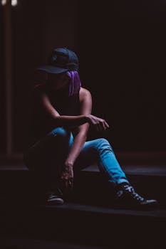 一名女子穿着休闲装，在光线昏暗的环境中若有所思地坐着