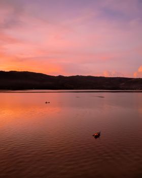 A tranquil scene of a sunset over Lake Sauce in Peru, with silhouetted mountains.