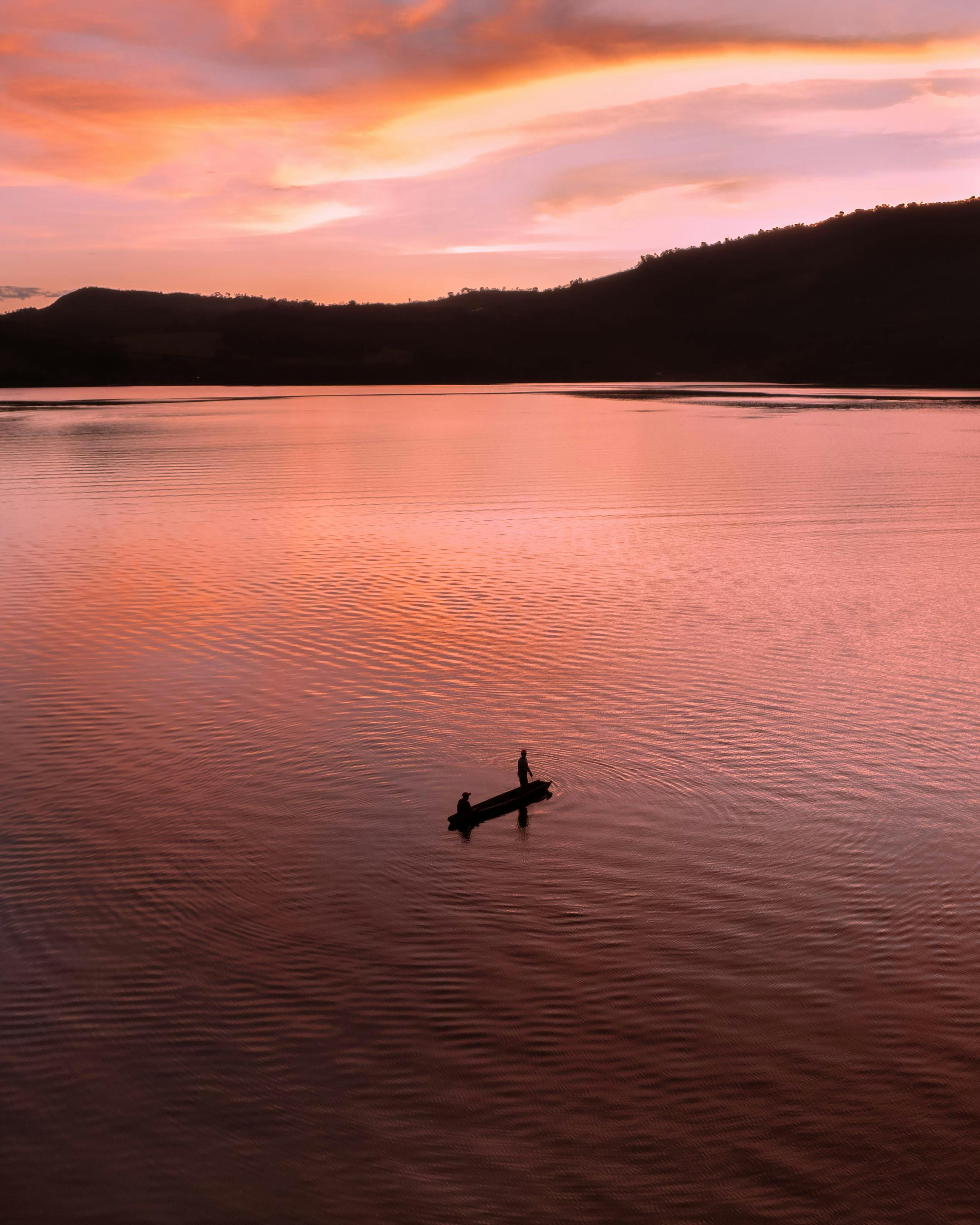 A beautiful sunset over Lake Sauce in Peru, highlighting a silhouetted boat and tranquil waters.