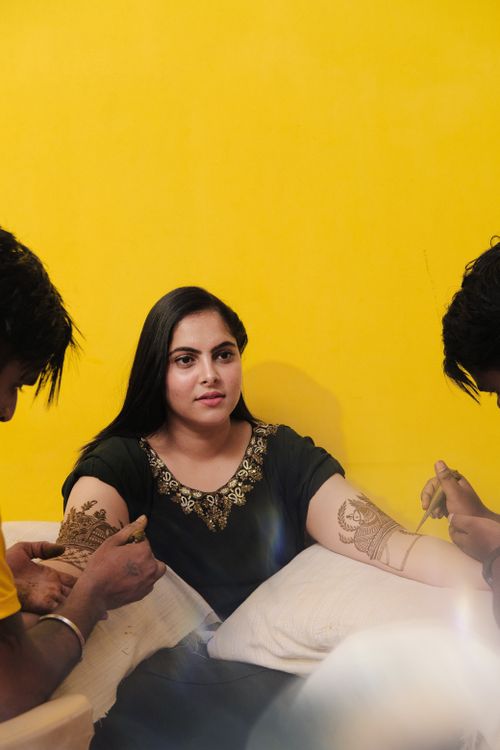 Free Woman getting Mehndi design applied by artists, showcasing Indian culture. Stock Photo