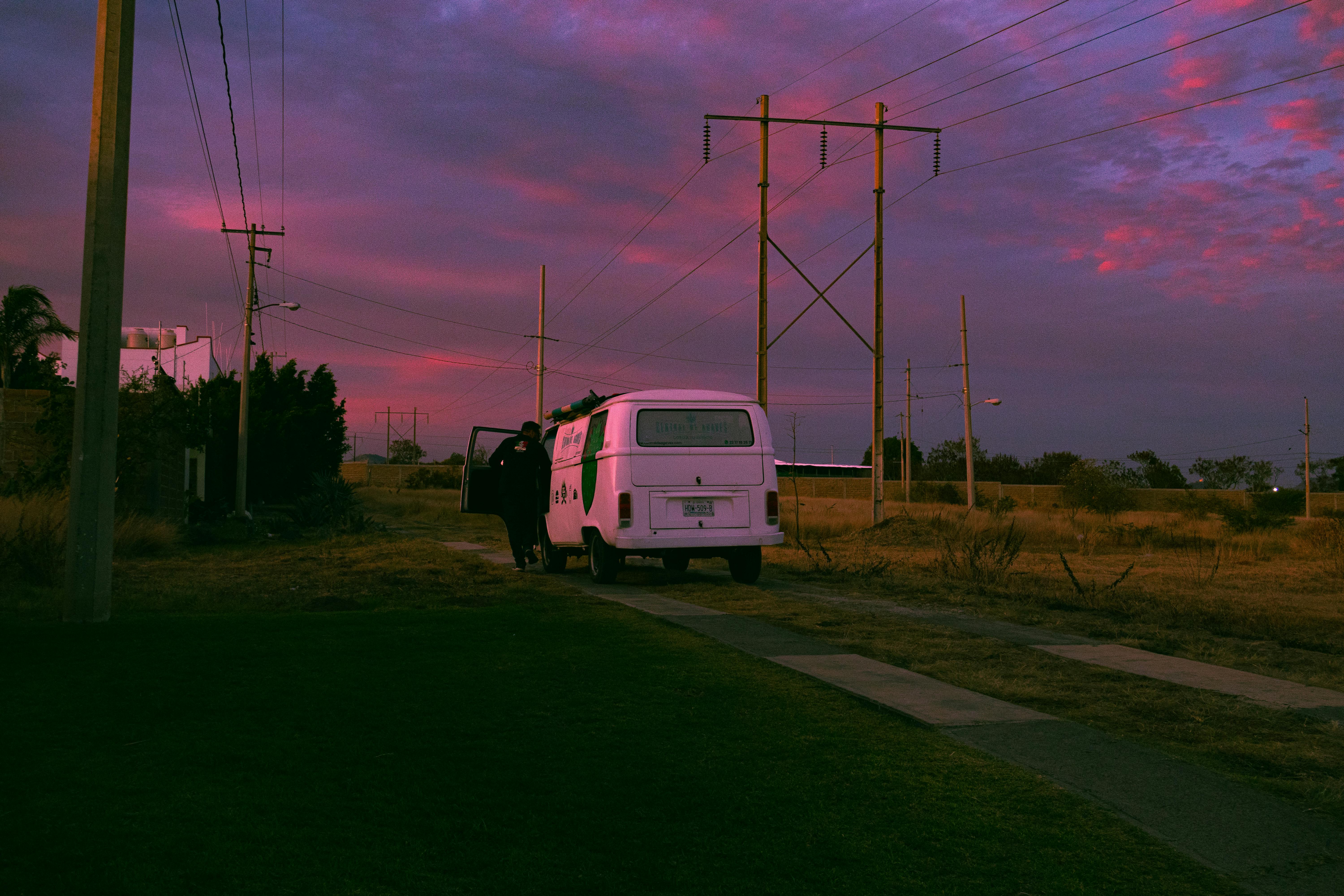 White van parked on rural road under a vibrant purple sky at twilight, creating a picturesque scene.