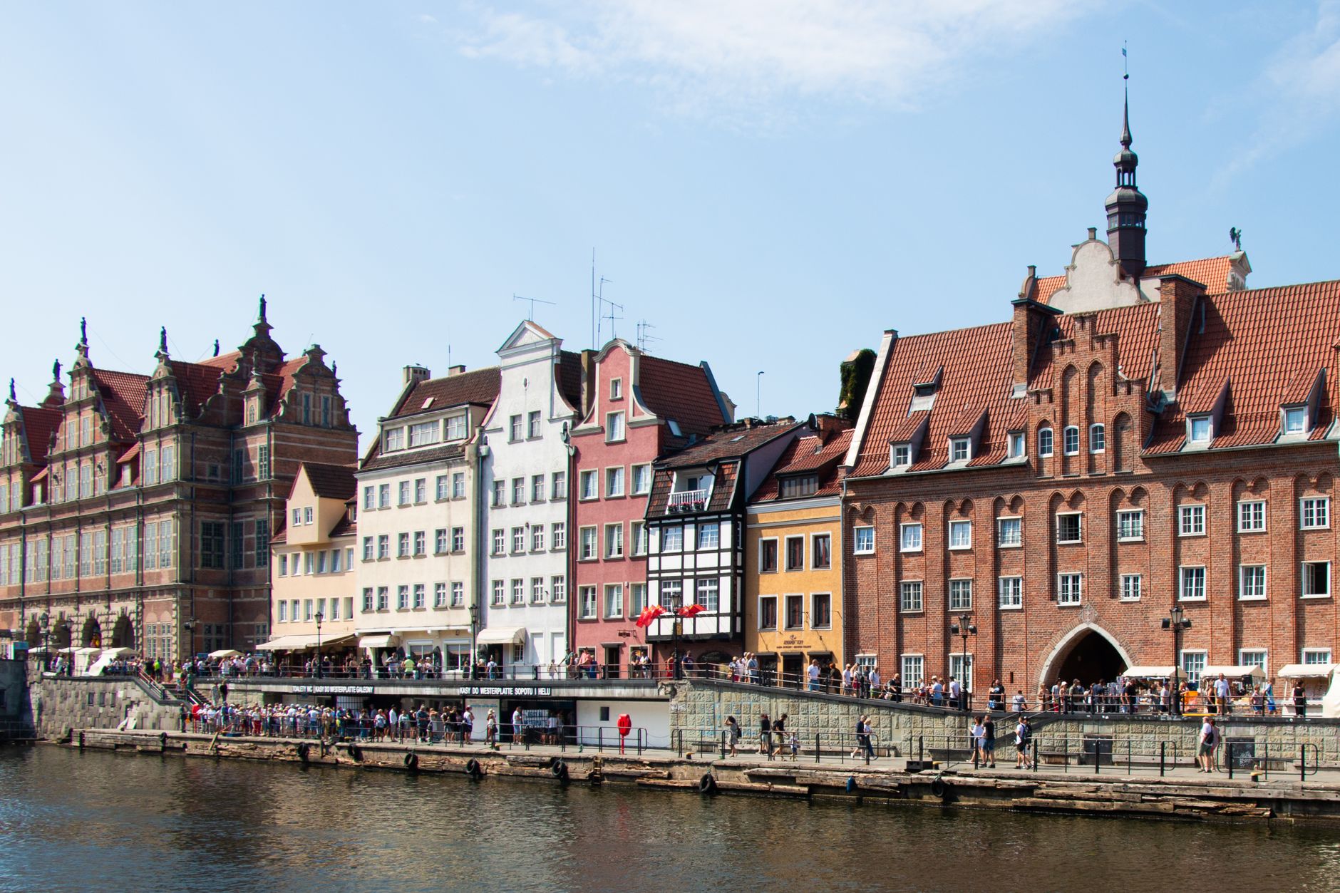Charming view of Gdańsk's historic waterfront lined with colorful buildings and lively visitors. — photo by Konpasu.de Blog / Pexels