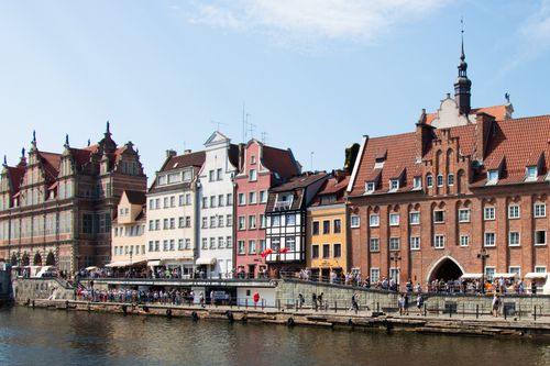 Free Charming view of Gdańsk's historic waterfront lined with colorful buildings and lively visitors. Stock Photo