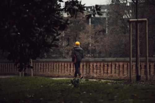 Free A person walks in a park in Padova, Italy, wearing a yellow hat and winter coat. Stock Photo