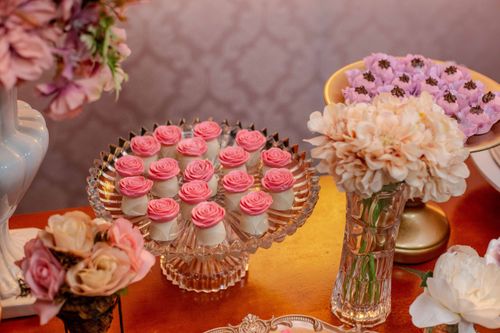 Free Charming dessert table with pink rose-topped sweets and floral decorations. Stock Photo