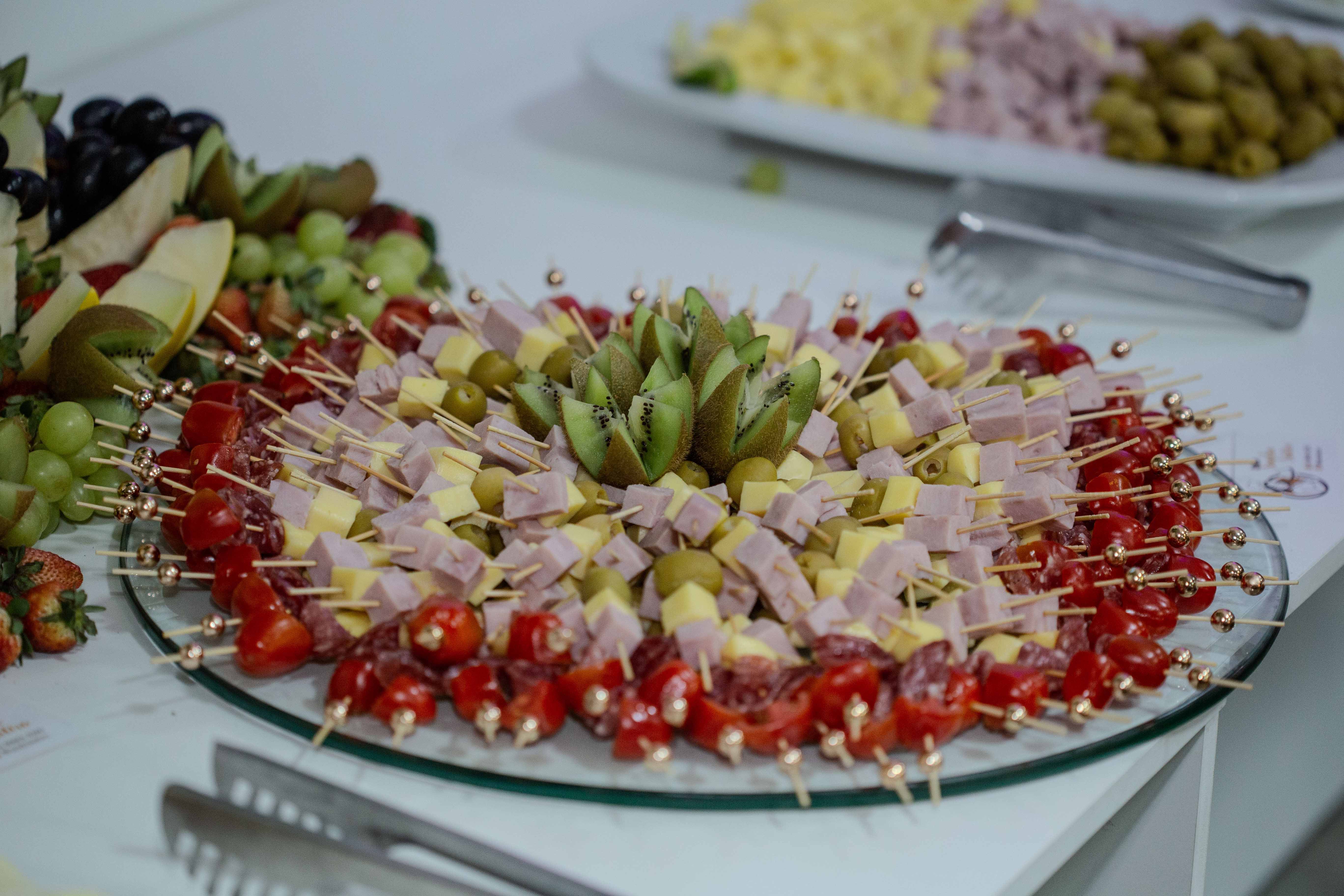 Vibrant platter of fruit and cheese skewers with kiwi, olives, and tomatoes, perfect for snacking.