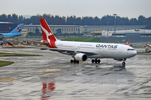 Qantas Airbus A330 taxiing on a rainy airport runway. Ideal for travel and aviation themes.