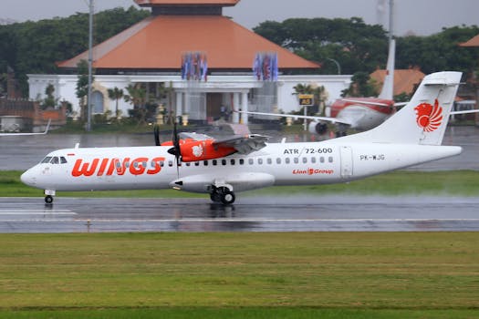 Lion Air ATR 72-600 plane with propellers on a rainy airport runway.