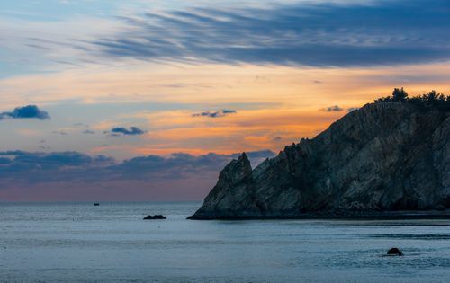 Free Serene view of a coastal cliff with vibrant sunset hues over the ocean. Ideal for nature and travel enthusiasts. Stock Photo