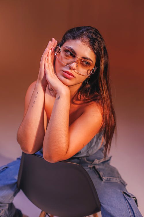 Woman in Jean Crop Top and Jeans Sits on Chair