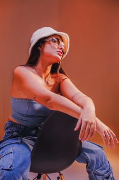 Fashionable young woman in bucket hat and denim poses in a studio setting.