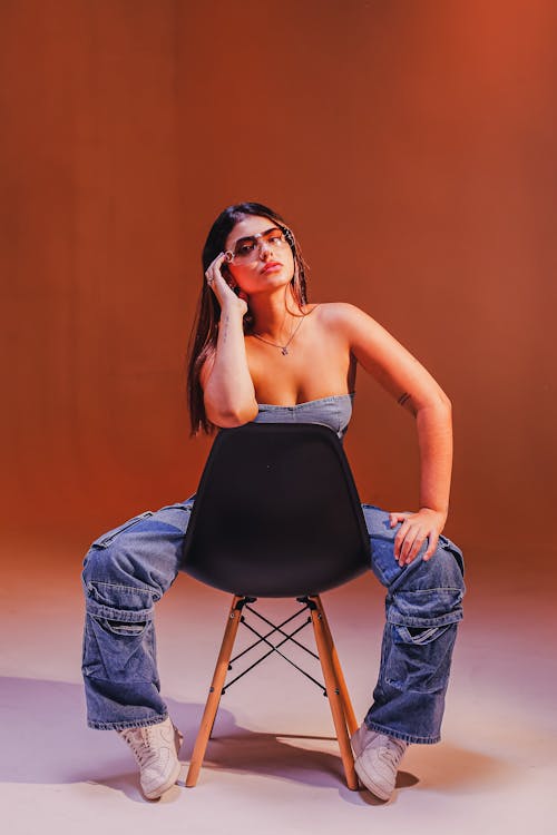 Studio Shot of a Young, Fashionable Woman Sitting on a Chair 