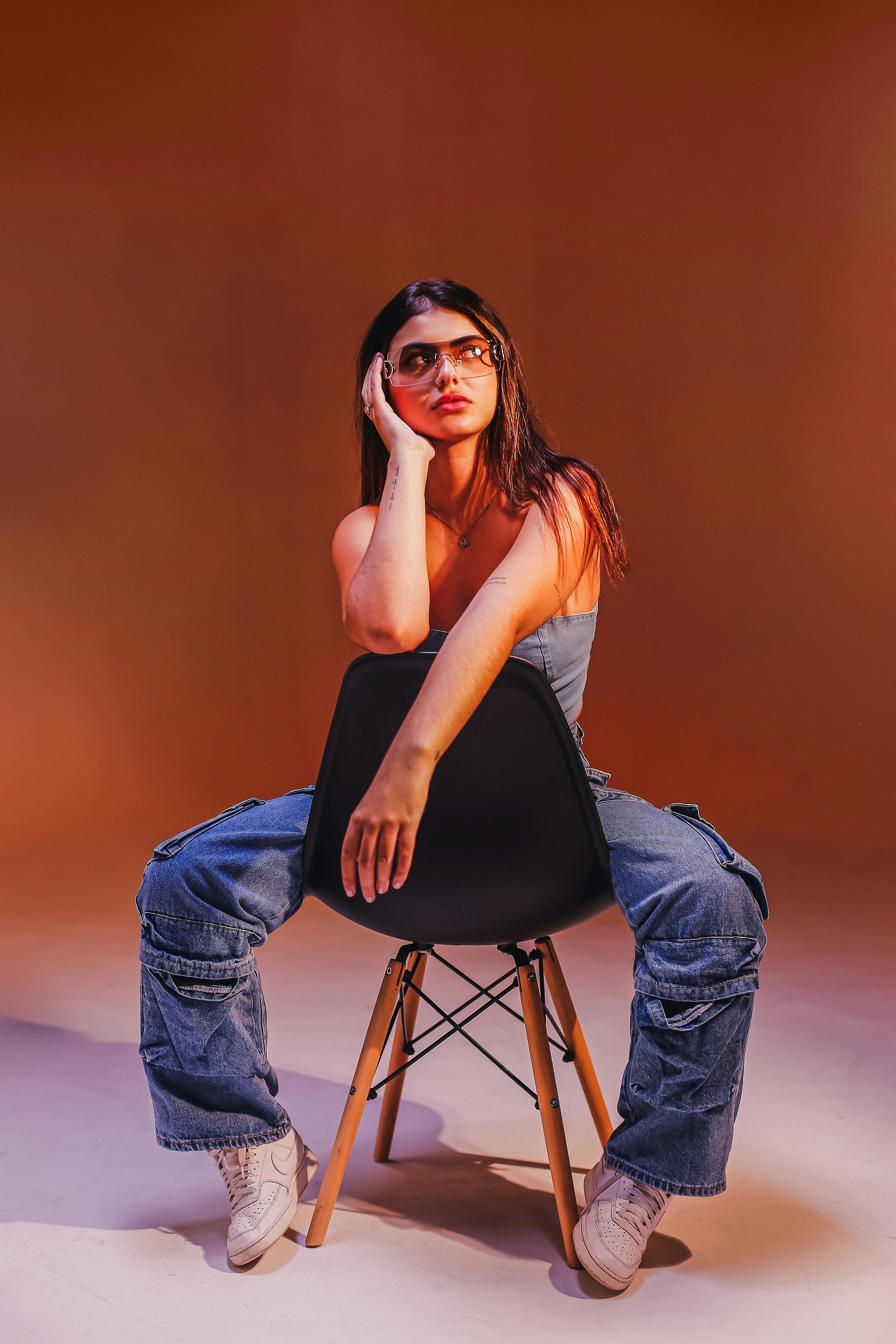 A fashionable woman poses indoors in trendy denim cargo jeans and trainers.