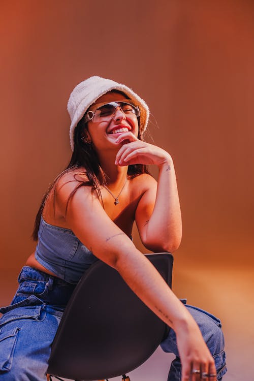 A woman in a hat and jeans sitting on a chair