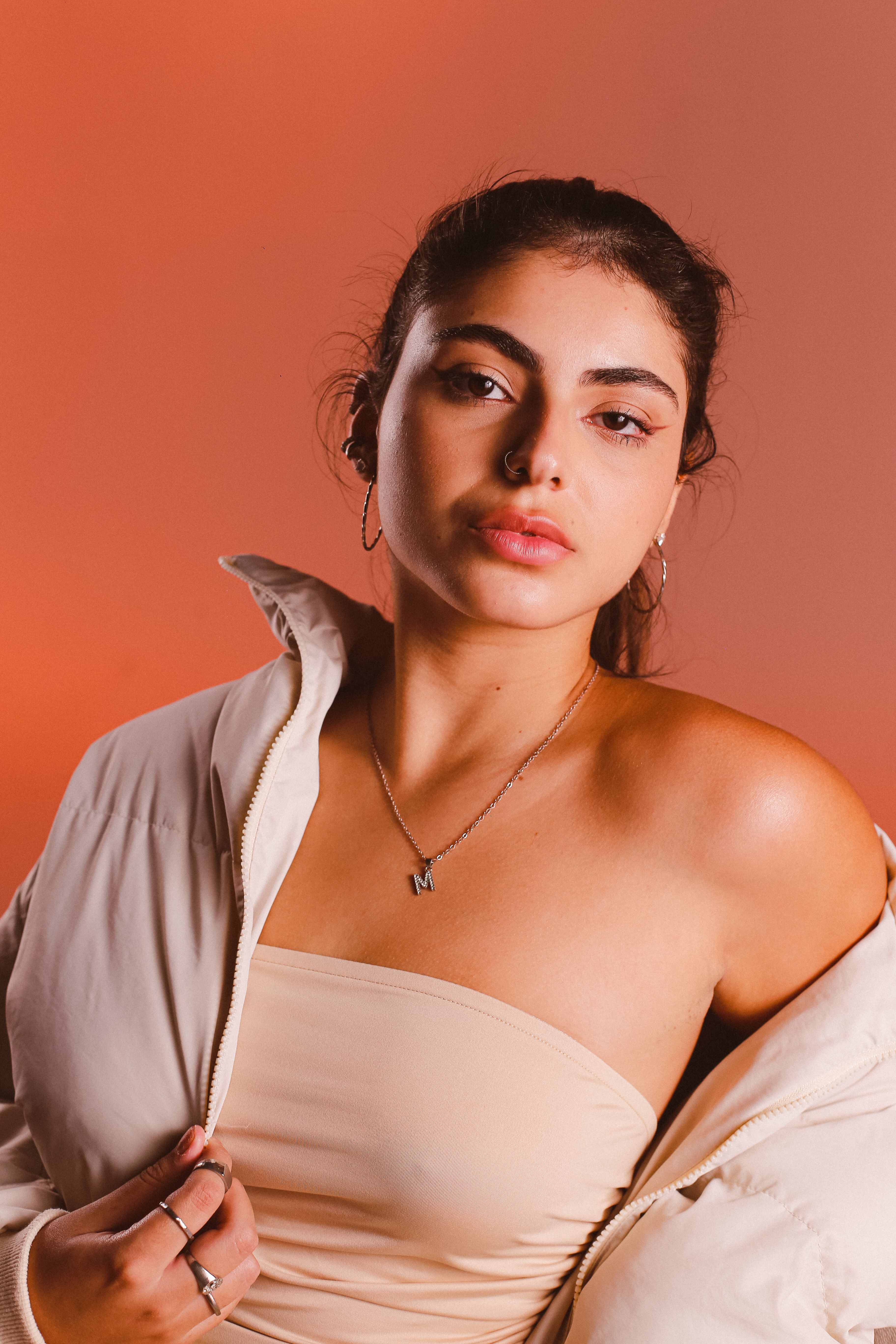 Stylish portrait of a woman in a beige outfit against a warm background.