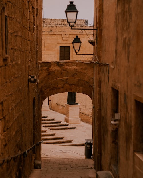 View of an Empty Walkway between Brown Walls of Old Buildings 