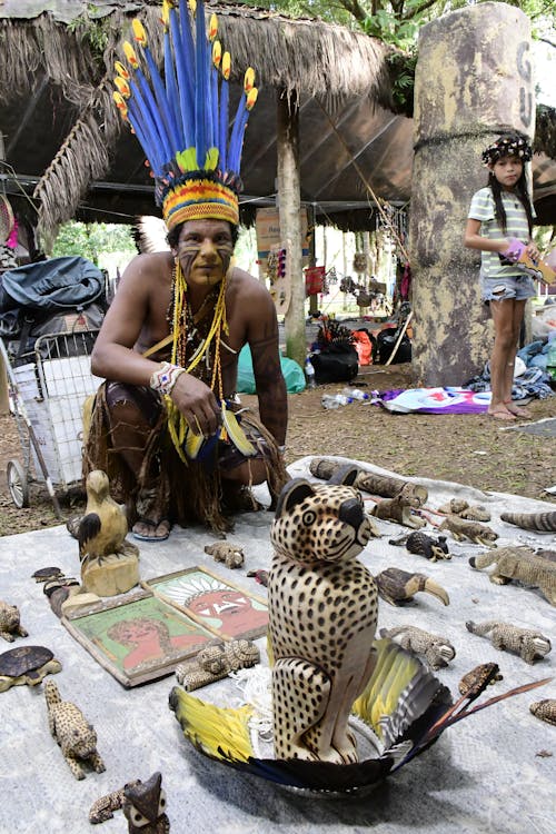 A Man Selling Handmade Carved Statues at a Market