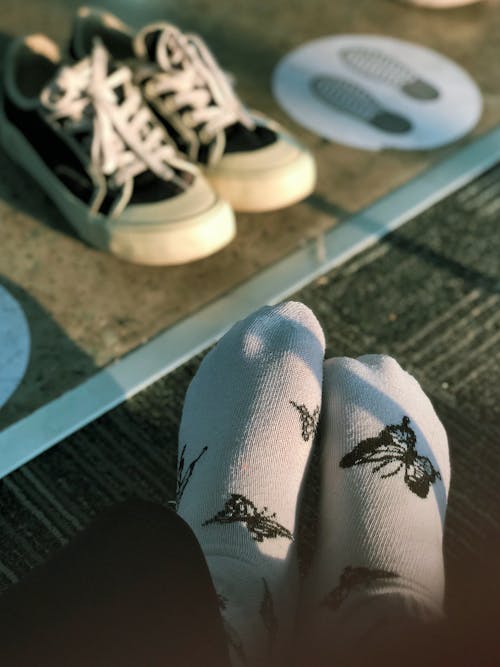 Feet of a Person Wearing White Socks with Black Butterflies