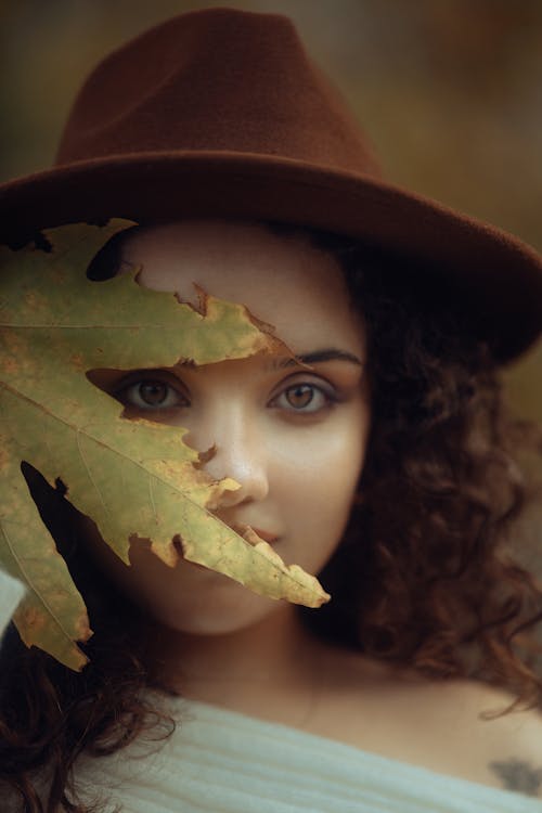 Pretty Brunette Wearing a Fedora Standing behind a Leaf