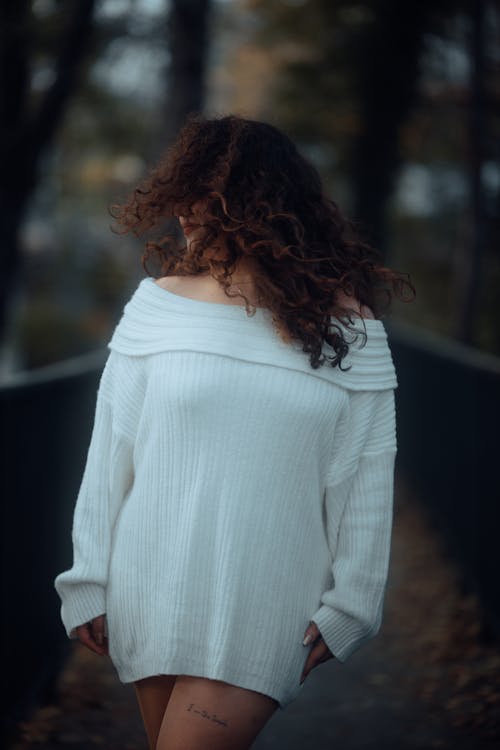 A woman in a white sweater standing on a bridge