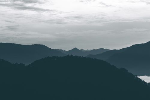 Free Tranquil view of rolling hills and mountains under a cloudy dusk sky. Stock Photo
