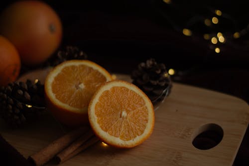 A cutting board with oranges and pine cones