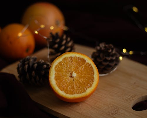 Pine Cones and a Halved Orange Lying on a Cutting Board