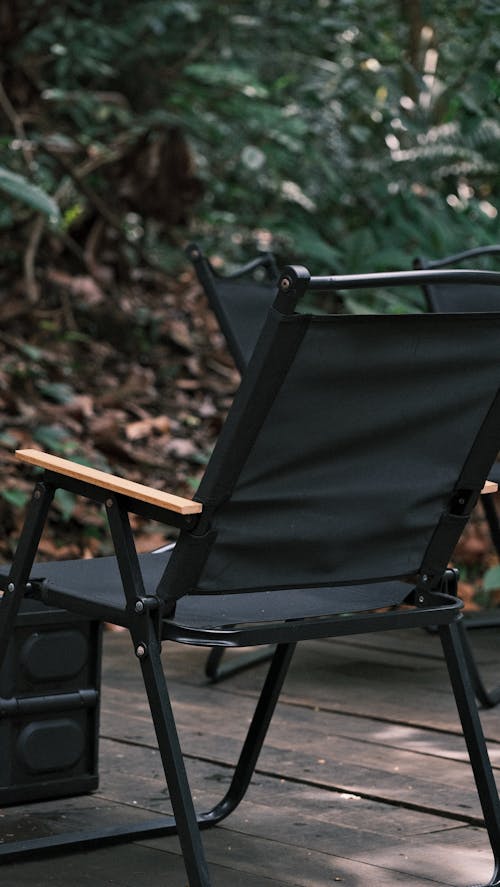 A black folding chair sits on a wooden deck