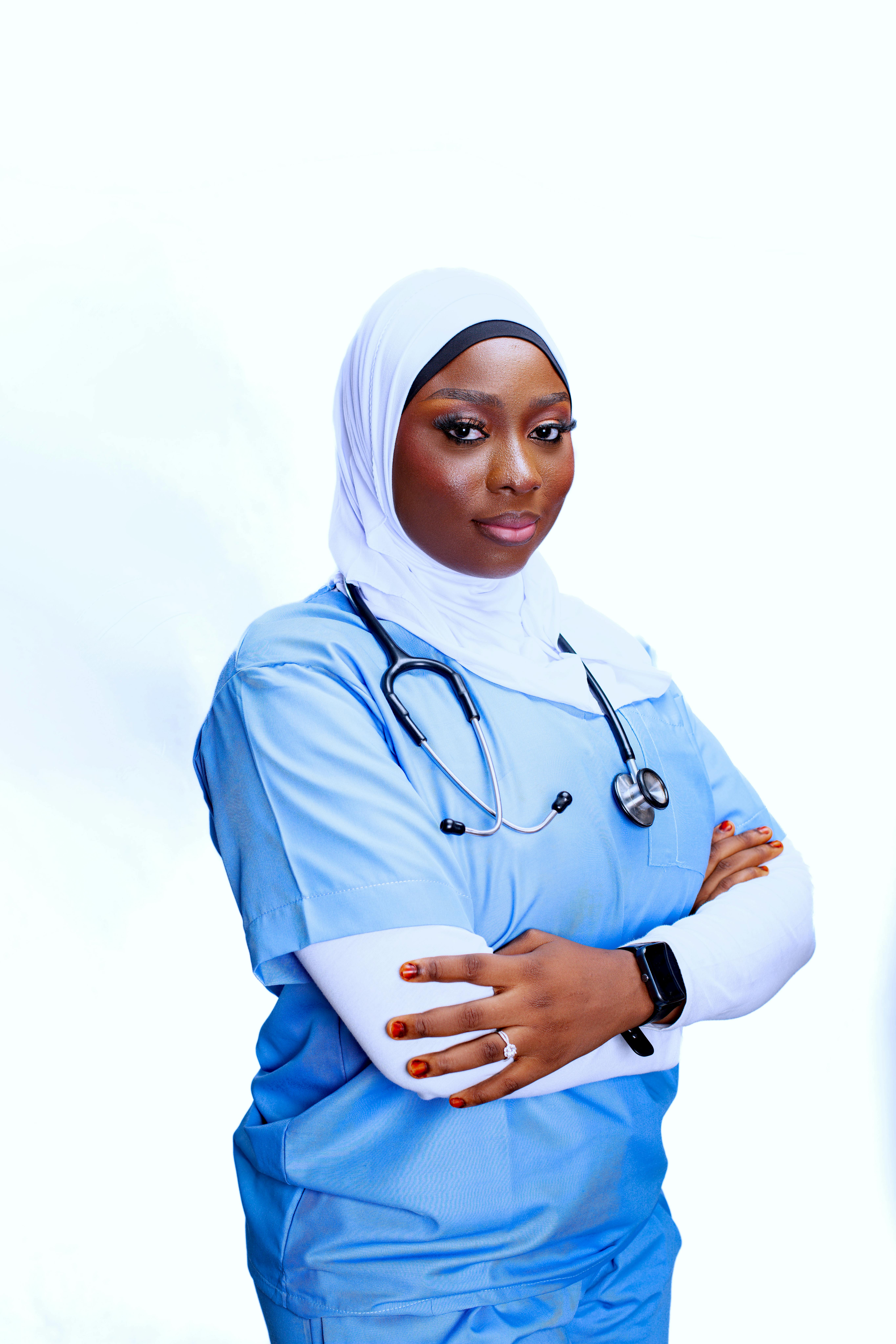 Portrait of a confident female nurse wearing a hijab and scrubs, arms crossed with a stethoscope.