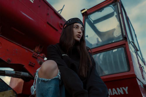 Young Woman Sitting next to a Heavy Construction Machinery 