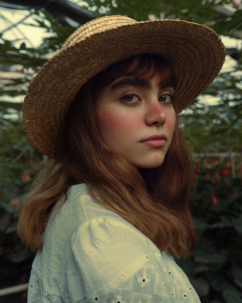 Close-up of a Woman in a Hat and White Shirt