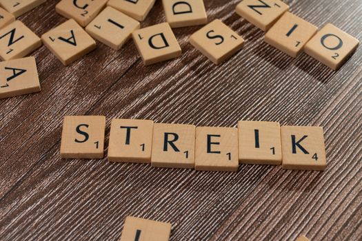 Wooden letter tiles spelling 'Streik' on a textured wooden surface, top view.