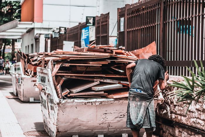 Worker collecting materials from a waste container, related to lead cost for junk removal Google Ads