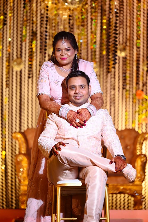 Smiling Man Sitting and Woman Standing behind in Traditional Clothing