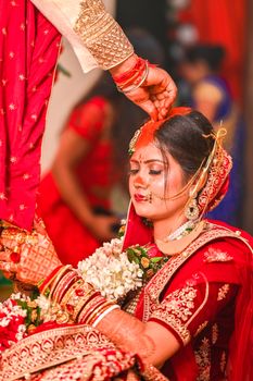A vibrant Indian bride in a red sari during an auspicious wedding ritual.