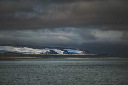 A view of the ocean and mountains under a cloudy sky