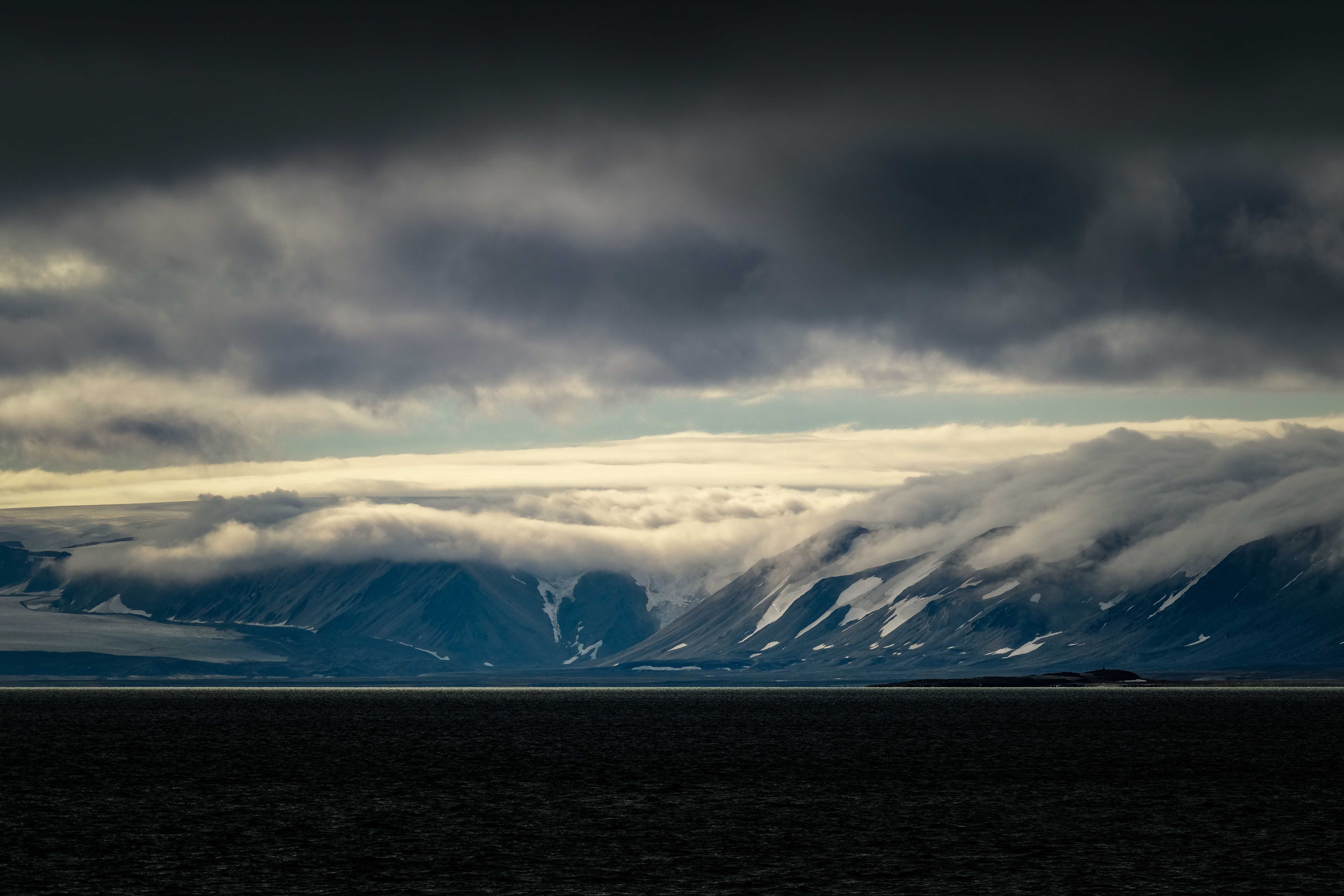 Rocky Hills Covered with Clouds by the Shore · Free Stock Photo