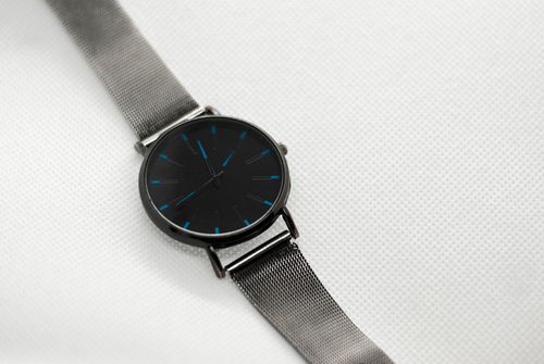 Free Minimalist silver wristwatch with mesh strap placed on a white textured surface for fashion and timekeeping themes. Stock Photo