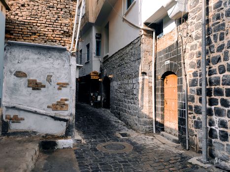 Explore the rustic charm of a historic alleyway in Sur, Diyarbakır with stone and brick walls.