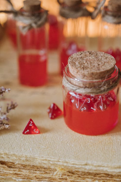 Free Captivating close-up of vibrant red dice submerged in glass jars, ideal for gaming themes. Stock Photo